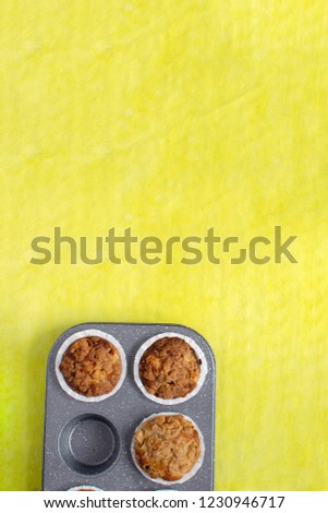 Homemade baking concept - fresh baked muffins on cooling rack, minimal picture, bright yellow background, background, top view, copy space.
