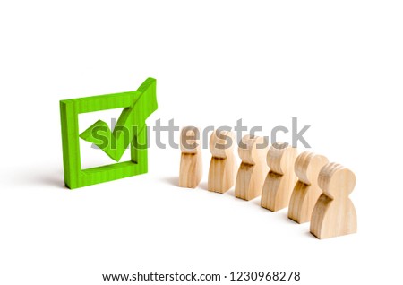 wooden human figures stand together next to a green tick in the box. The concept of elections and social technologies. Volunteers, parties, candidates, constituency electorates. Selective focus