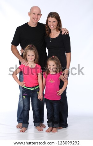 Attractive family of four, with mother, father and two daughters, wearing pink and black in studio on white isolated background