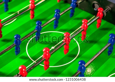Table hockey, mini soccer background. Plastic board game. Colored figures. Funny active family sport game. Red and blue figures. Relax and activity time, sports competition. Green field, players team