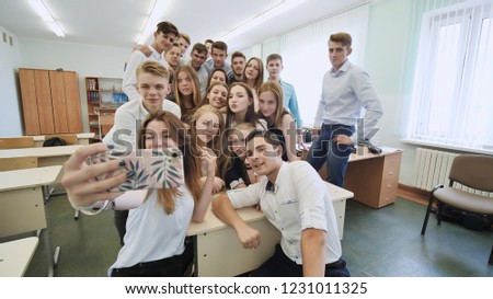 Young happy cheerful students making selfie in school class.