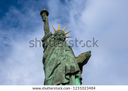Statue of Liberty at Isle of the Swans in Paris (France) against blue sky white clouds background.