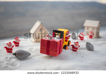 Miniature Gift Box by Forklift Machine on snow ,Determined Image for Christmas Holiday and Happy New Year Gift Celebration concept. Selective focus