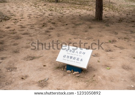 Funny message to keep off lawn and don't pick flowers in middle of bare dirt and soil