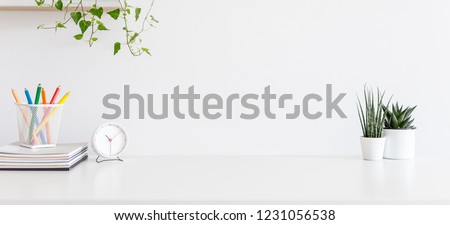 Front view white desk with supplies, alarm clock, coffee mug and copy space. Royalty-Free Stock Photo #1231056538