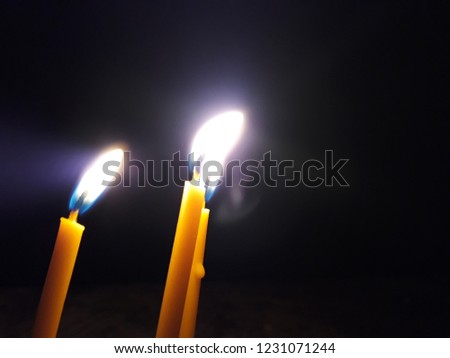 Candles Burning at Night. White Candles Burning in the Dark with lights glow.