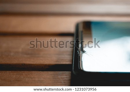 A broken cell phone on a wood table. 