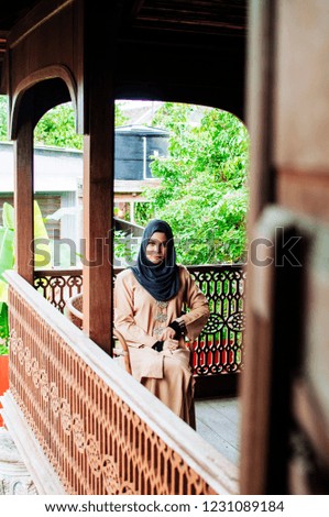 Portrait of happy young muslim woman brown hijab over blurred the green field background.
