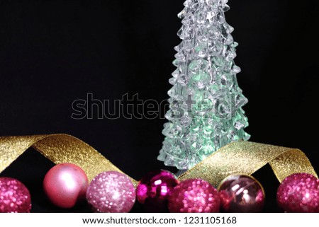 Pink colorful glitter Christmas decorations and gold ribbon and Christmas tree
on black background
