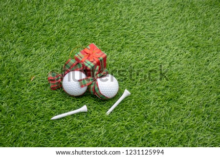 Golf Christmas ball with gift on green grass