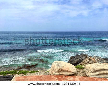 Beautiful coastal view of the aqua blue green  sea and rocks, a background of waves crashing as they come to hit the rocks, in Mexico.