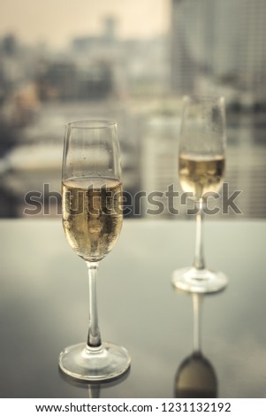 Glasses of champagne at rooftop restaurant with city views.