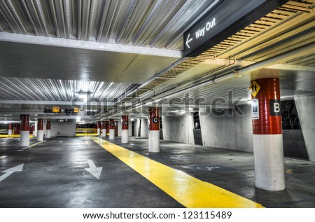Empty new parking interior with red and white columns and yellow pedestrian walkway.