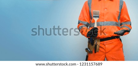 A painter worker is holding a paint brush in hand isolated on blue background with copy space. Under construction concept background.