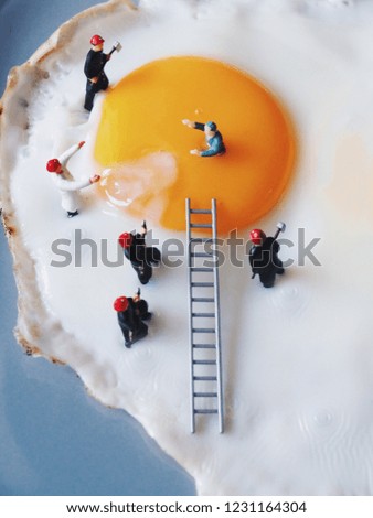 Close up miniature people explorer fall in yolk then the team trying to helping.
