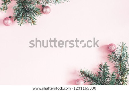 Christmas composition. Frame made of fir tree branches, pink balls on pastel pink background. Christmas, winter, new year concept. Flat lay, top view, copy space