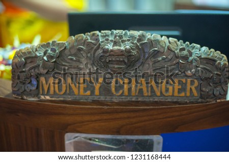 Balinese traditional handmade woodcraft with money changer signage display in a shopping mart at Kuta Walk Mall. Kuta Beach, Bali. Indonesia. selective focus blur background.