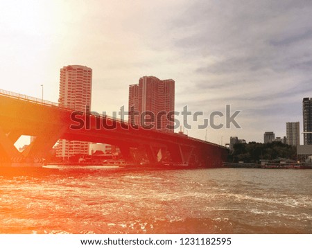 Bridge road across the Chao Phraya river at Thailand on building and city background with sunlight flare for copy space.