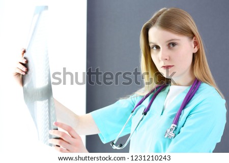 Doctor woman surgeon  examining x-ray picture while standing near window  in clinic or hospital. Medicine and healthcare concept. Physician at work