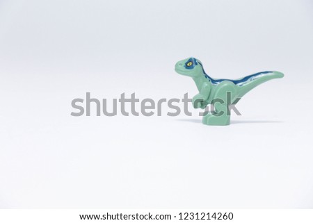 
small dinosaur on a bey background. dinosaur toy protection. miniature toys concept