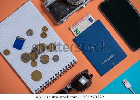 various things for travel on a pink and blue background. Soviet retro camera and wallet with money, sunglasses and smartphone with a passport