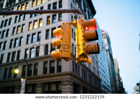 Yellow equipment for controlling transport on intersection of business district with high corporate building,red sign on traffic light hanging over crossroads in megalopolis for regulating city