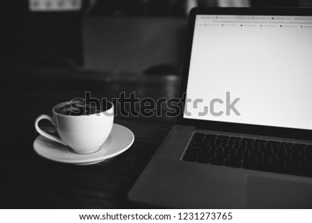 A cup of cappuccino coffee or chocolate cacao in a white cup with laptop on table. Royalty high quality free stock photo of drink capuccino or latte coffe with laptop for working in office