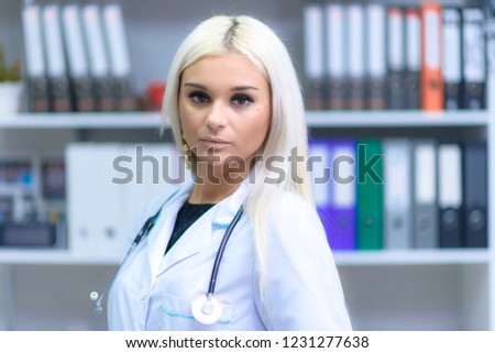 Concept portrait of a beautiful girl doctor in the office at the table listens.
