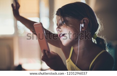 She loves music. Little school girl using smart phone and listening music. Close up. Copy space.