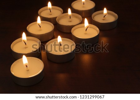 Many burning candles on table in darkness with room for text. Romance, celebration and memorial symbol.