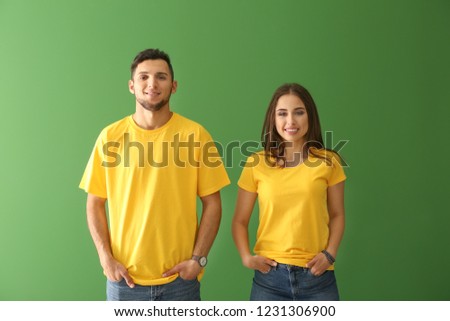 Young man and woman in stylish t-shirts on color background