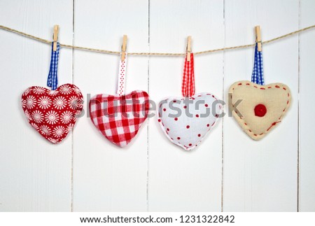 Four hearts hanging in front of a white wooden wall