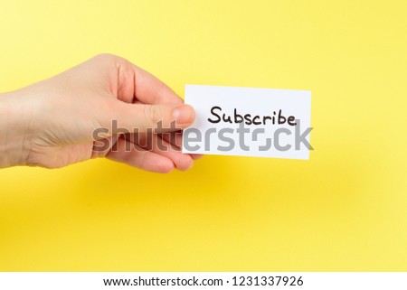 Subscribe text on a card in woman hand  on a yellow background.