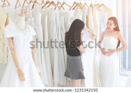 An asian woman is trying her wedding dress and expressed her feeling, dressmaker is assisting professionally.