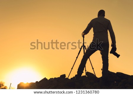 Silhouette of photographer taking pictures at sunset. Image with copy space.