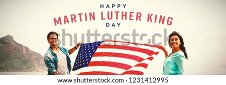 happy Martin Luther King day against portrait of couple holding american flag on beach