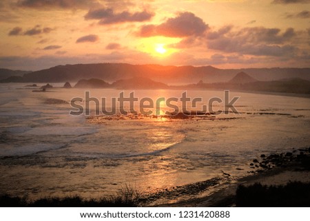 Seeing sunset along the beach and coast, yellow light in the evening, wide scene of sky and sea.