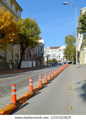 Bicycle path between the sidewalk and the roadway on a narrow street in the old part of the city. Healthy lifestyle. Cityscape on an autumn day with yellow-green trees and blue sky, vertical frame