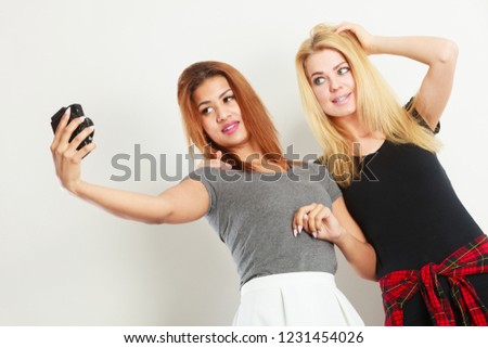 Technology internet and happiness concept. Young women blonde and mixed race taking self picture selfie with camera
