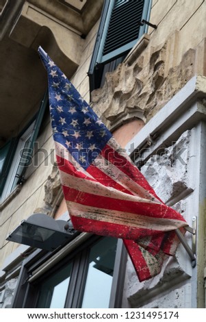 Old worn American flag on a building wall