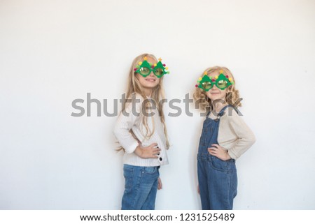 Two little girls in funny glasses in the form of Christmas trees.