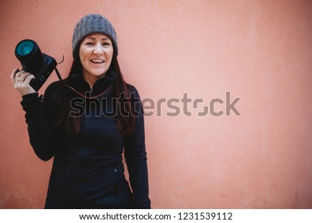 Young woman smiling and holding camera, photographer with camera