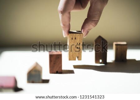 Hand choosing mini wood house model from model, selective focus, Planning to buy property. Choose what's the best. A symbol for construction ,ecology, loan concepts