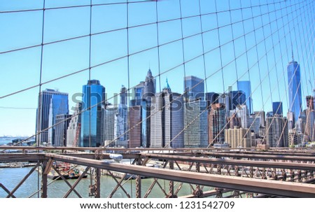 Urban cityscape with bright blue sky seen through vertical and diagonal bridge support cables and wires