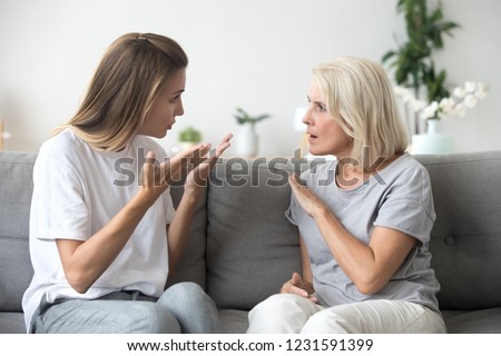 Angry young woman has disagreement with annoyed old mother in law, grown daughter arguing fighting quarreling with senior elderly mom, different age generations bad relations family conflict concept Royalty-Free Stock Photo #1231591399