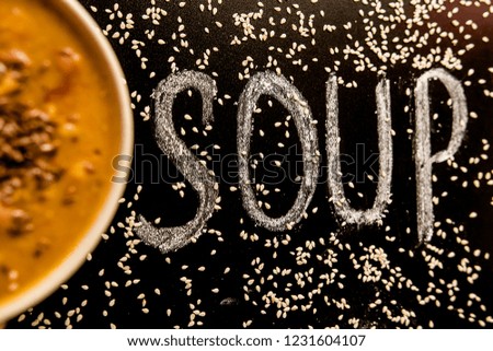 soup plate lentils broth puree orange black inscription chalk flax seeds sesame menu restaurant kitchen table board