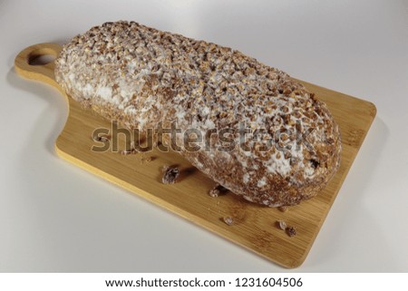 Pound cake with walnuts and raisins on a cutting board. Sprinkled by powdered sugar and crushed walnuts.