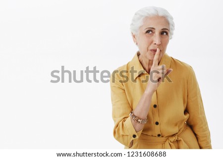 Waist-up shot of wise and creative charismatic elderly mother with white hair smiling intriguing and myseteriously saying shh making surprise showing shush gesture with index finger over mouth