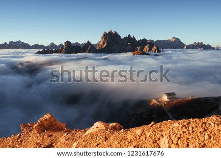 Extremely brittle surface under photographer who takes this picture. Photo from the edge of the hill and with beautiful mountains with lots of clouds and building on the right.