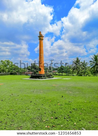 A big pillar in the green garden with blue sky